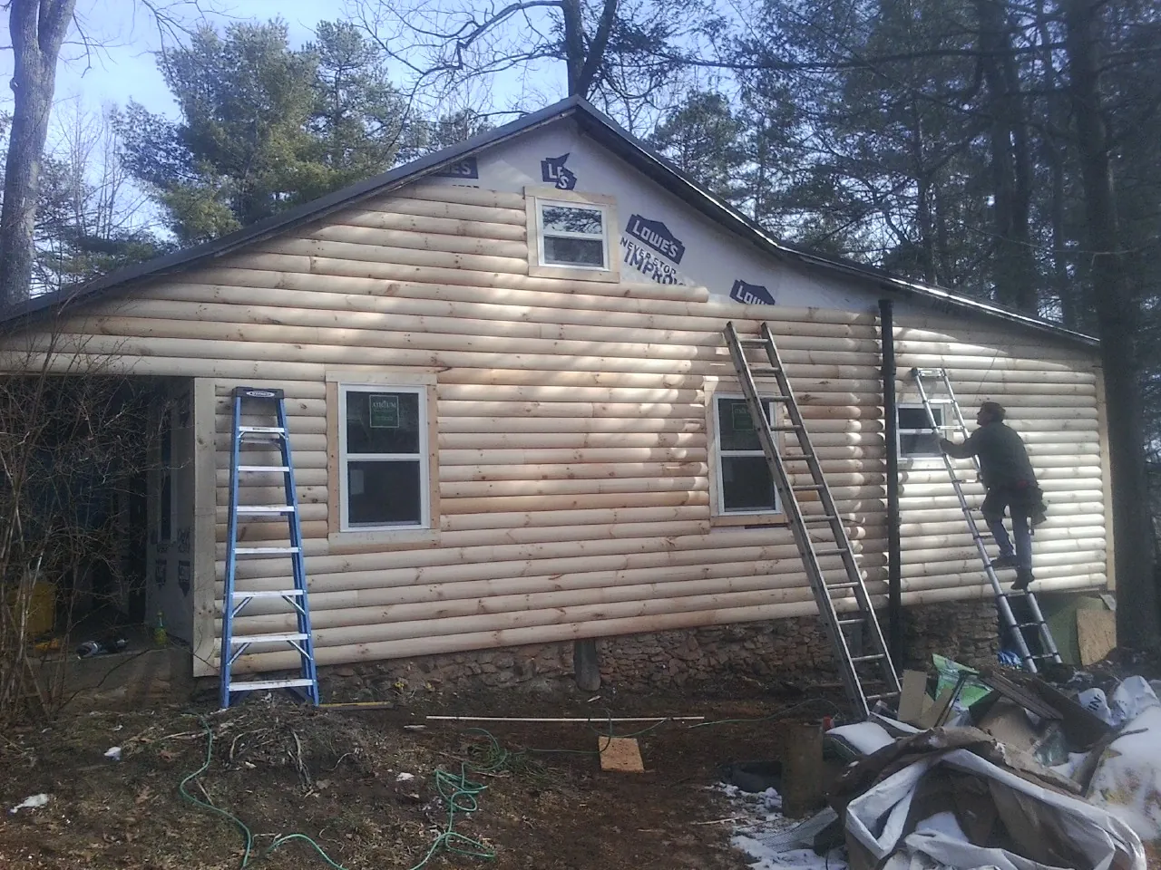 Ladders set against fresh log siding during an exterior remodel in Roslyn Heights