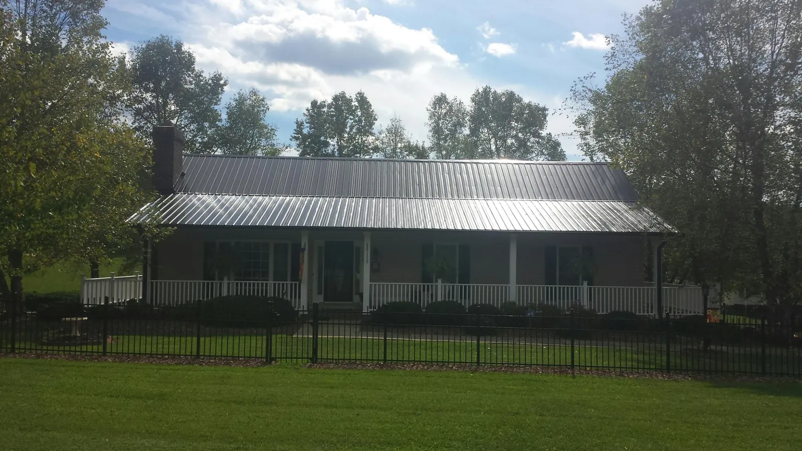 Gray metal roof on a brick ranch with a full width front porch — Gutter Guard Installation work by our crew in Roslyn Heights