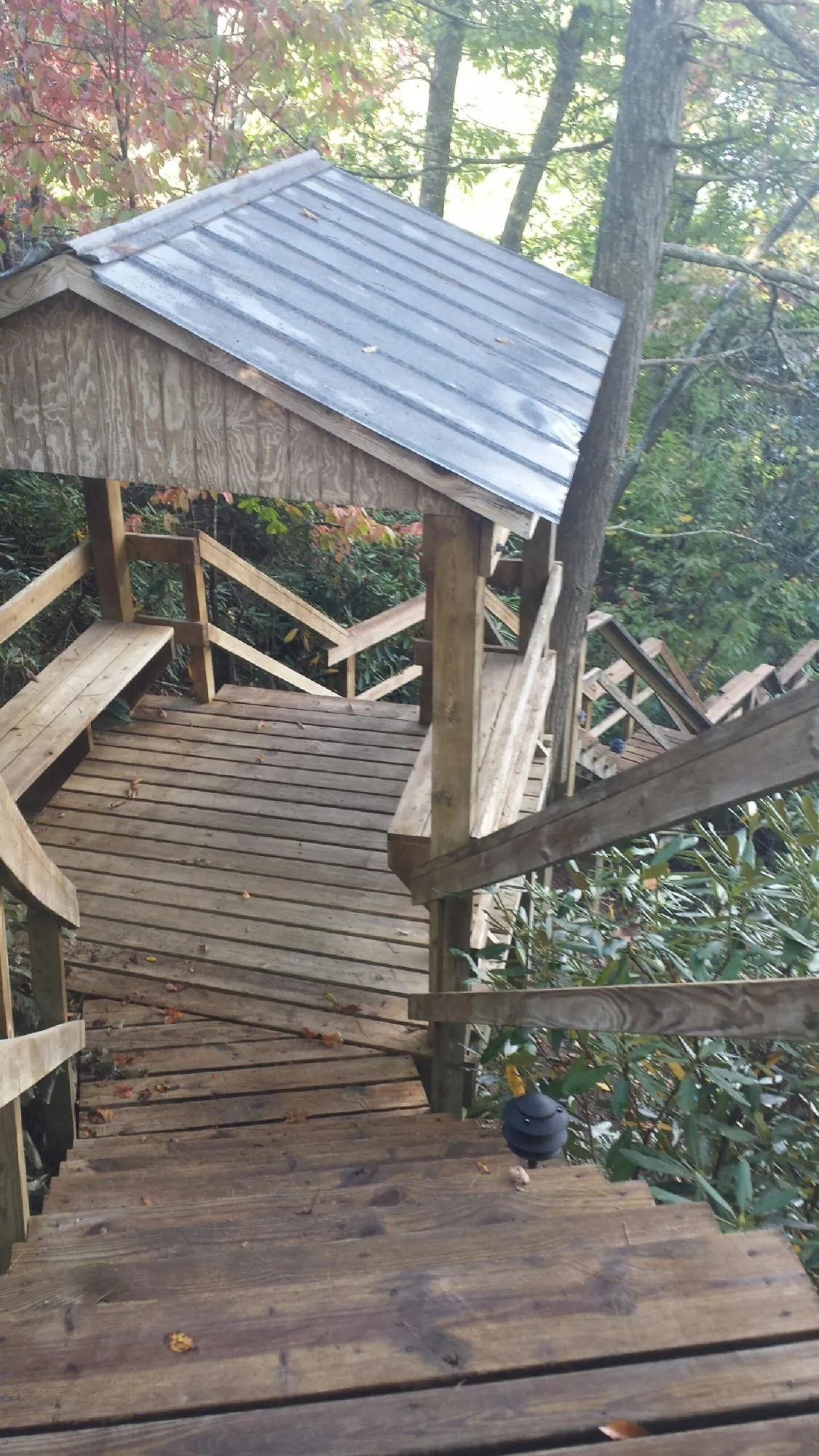 Metal roofed shelter over wooden steps on a wooded walkway — Skylight Repair & Installation work by our crew in Roslyn Heights