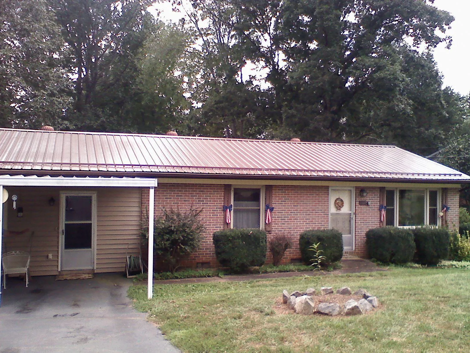 Bronze metal roof and carport on a brick ranch home — Roof Repair work by our crew in Roslyn Heights