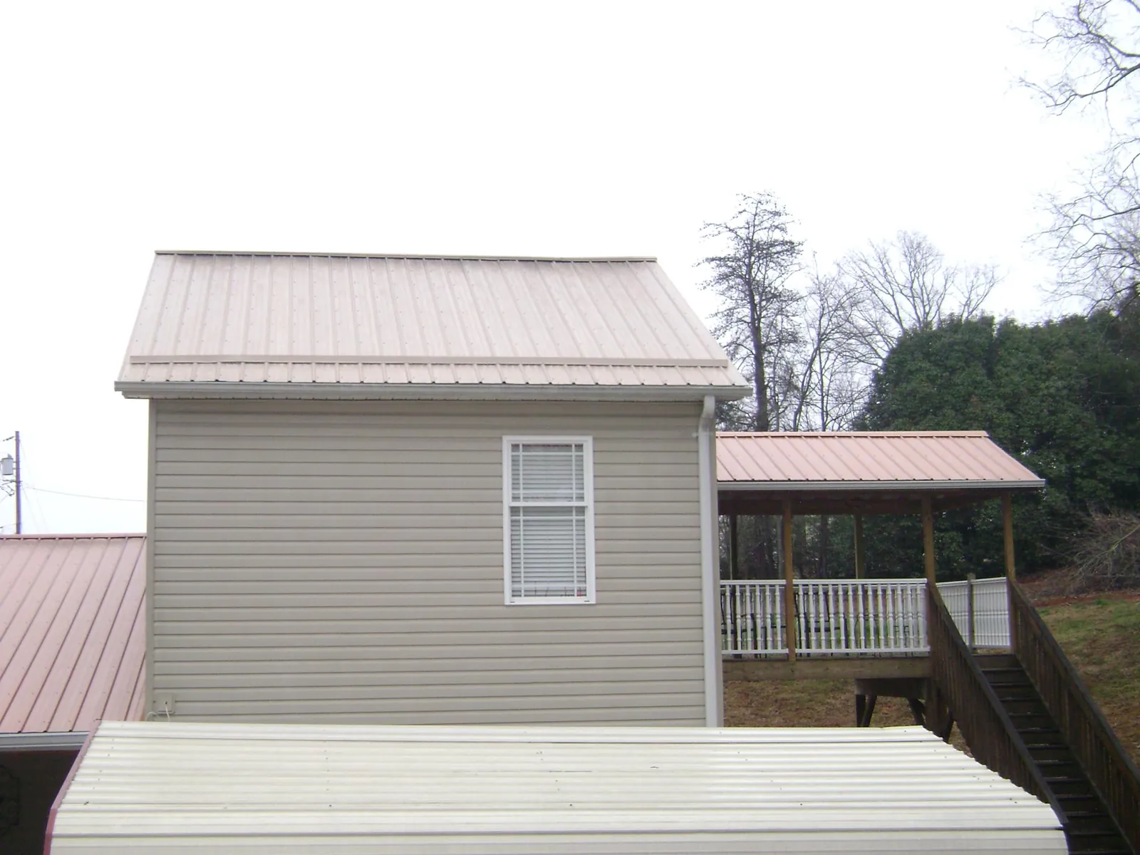 Tan metal roofs on a two story addition and attached porch, from a Roof Replacement job in Roslyn Heights